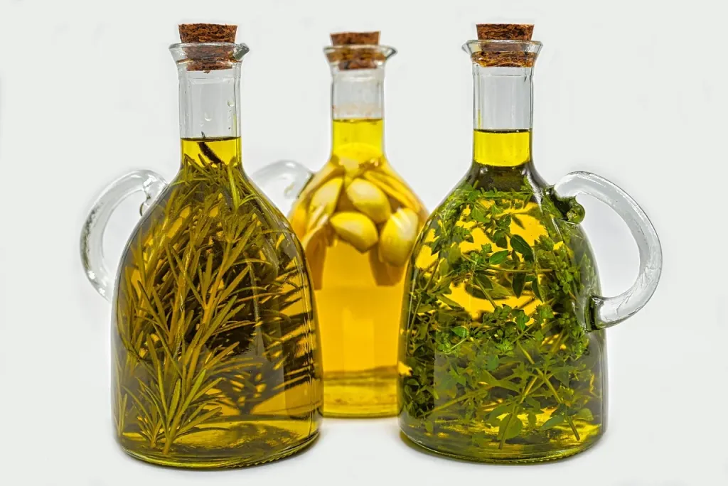 Szklane karafki z olejem roślinnym wzbogaconym ziołami, podkreślające naturalny skład i wysoką jakość produktu.